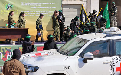 Hamas operatives escort four Israeli hostages on a stage before handing them over to a team from the Red Cross in Gaza City on January 25, 2025.  (Photo by Omar AL-QATTAA / AFP)