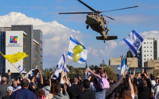 People wave flags as a military helicopter transporting the four newly-released Israeli hostages lands at Rabin Medical Center in Petah Tikva on January 25, 2025. (Yossi Zamir/AFP)