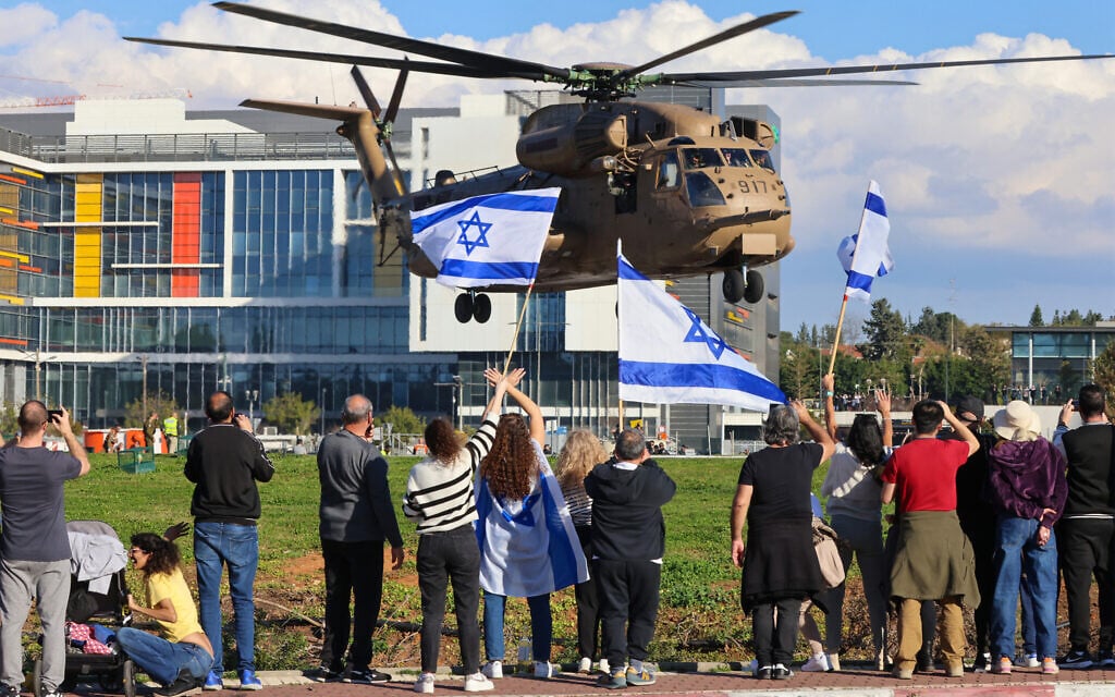 People wave Israeli flags as a military helicopter transporting the four newly-released hostage soldiers lands at the Rabin Medical Center in Petah Tikva on January 25, 2025. (Yossi Zamir/AFP)