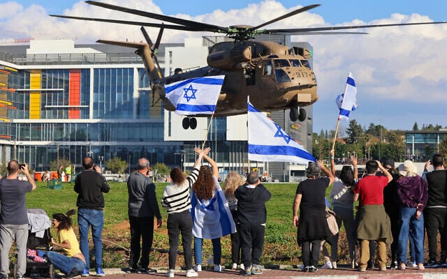 People wave Israeli flags as a military helicopter transporting the four newly-released hostage soldiers lands at the Rabin Medical Center in Petah Tikva on January 25, 2025. (Yossi Zamir/AFP) People wave Israeli flags as a military helicopter transporting the four newly-released hostage soldiers lands at the Rabin Medical Center in Petah Tikva on January 25, 2025. (Yossi Zamir/AFP)