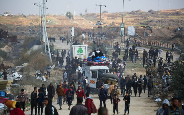 An Israeli tank is seen in the background as displaced Palestinians travel toward Gaza City through the Netzarim Corridor from the southern Gaza Strip on January 27, 2025. (Photo by Eyad BABA / AFP)