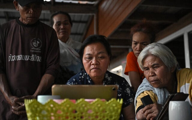 Wiwwaeo Sriaoun (C), the mother of Thai farm worker Watchara Sriaoun held hostage in Gaza, watches the news with relatives as she waits for the confirmation of his release, at her home in Udon Thani province, Thailand's rural northeast on January 30, 2025.  (Photo by Lillian SUWANRUMPHA / AFP)