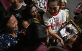 Wiwwaeo Sriaoun (L), the mother of Thai farm worker Watchara Sriaoun who was held hostage in Gaza, reacts as she receives an image of her son (R) being released, at her home in Udon Thani province, Thailand's rural northeast on January 30, 2025. (Lillian Suwanrumpha/AFP)