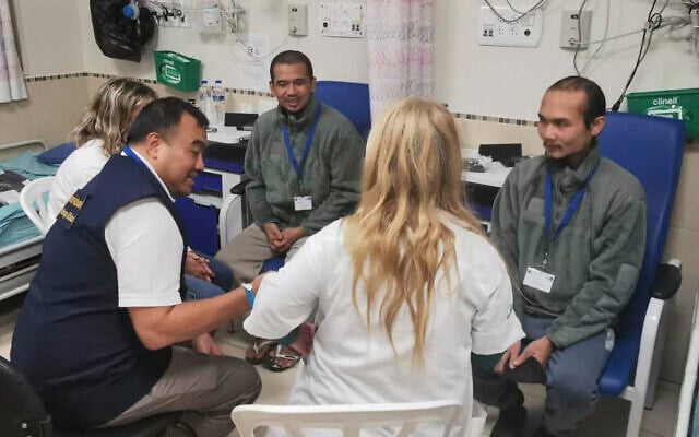 In this photo provided by Thailand's Foreign Ministry, two newly freed Thai hostages talk to a Thai officer, left center, and medical staff, at Shamir Medical Center in Israel on Sunday, Nov. 26, 2023. (Thailand's Foreign Ministry via AP )