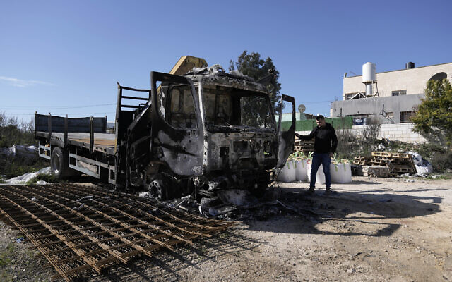 A Palestinian stands beside a truck that was torched in an attack by Israeli settlers in the West Bank village of Jinsafut, Tuesday, Jan. 21, 2025. (AP Photo/Majdi Mohammed)