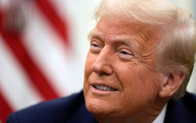 US President Donald Trump smiles as he signs executive orders in the Oval Office of the White House, in Washington, January 23, 2025. (AP Photo/Ben Curtis)