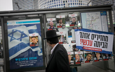 An ultra-Orthodox man walks by photographs of hostages held by Hamas in Gaza, posted in Tel Aviv. December 21, 2023. (Photo by Miriam Alster/FLASH90)