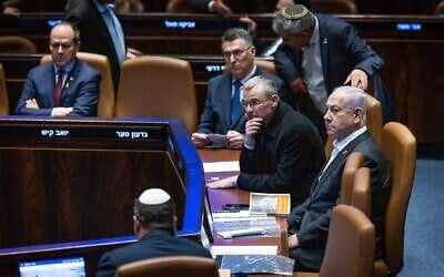Prime Minister Benjamin Netanyahu in the Knesset, on December 31, 2024. He left the hospital less than two days after prostate surgery to vote on a budget-related law. Yariv Levin is seated next to him. (Chaim Goldberg/Flash90)