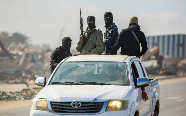 Masked Palestinian gunmen guard trucks loaded with humanitarian aid in Jabalia in the northern Gaza Strip, January 20, 2025. (Ali Hassan/Flash90)