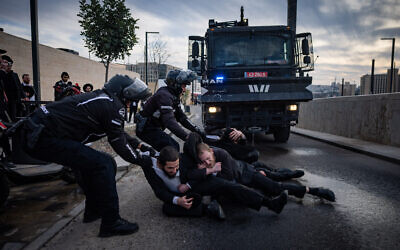 Police drag away ultra-Orthodox protesters who sat on the road during a demonstration against Haredi enlistment, outside a conference honoring ultra-Orthodox soldiers in Jerusalem, January 28, 2025. (Chaim Goldberg/Flash90)