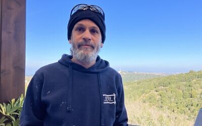 Shay Herz stands on the porch of his house in Mattat, northern Israel, with a view of Lebanon in the background on January 28, 2025. (Diana Bletter/Times of Israel)