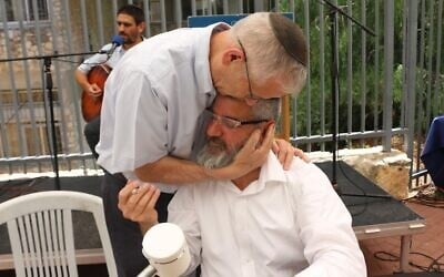 Rabbi Jeremy Stavisky hugs a teacher and scribe who wrote a Torah scroll in honor of Himmelfarb high school's fallen alumni. (Courtesy of Himmelfarb via JTA)