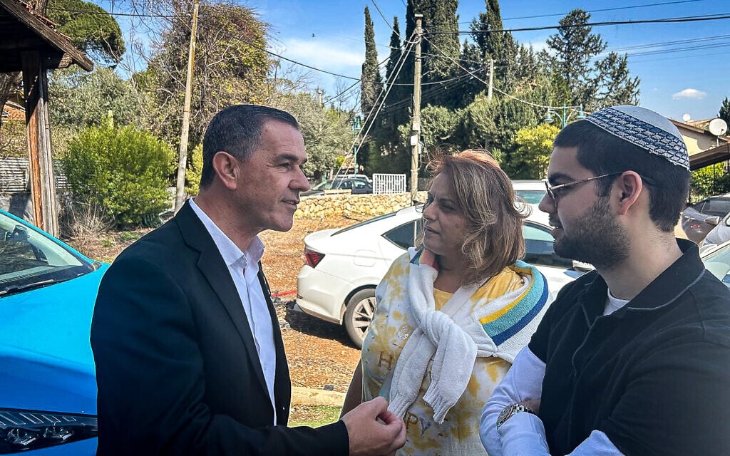 Kiryat Shmona mayoral candidate Eli Zafrani (left) speaks with two residents of the city outside his campaign HQ on election day, February 18, 2025 (Shalom Yerushalmi/Times of Israel)