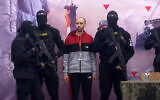 Hostage Tal Shoham, surrounded by armed fighters, stands on a stage in Rafah as he is released by the Hamas terror group in Rafah on February 22, 2025. (Screen grab/YouTube)