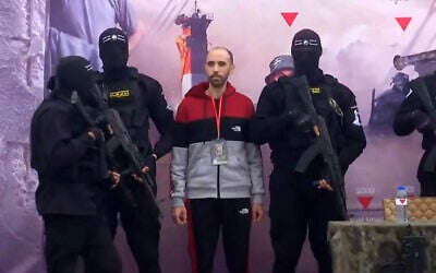 Hostage Tal Shoham, surrounded by armed fighters, stands on a stage in Rafah as he is released by the Hamas terror group in Rafah on February 22, 2025. (Screen grab/YouTube)