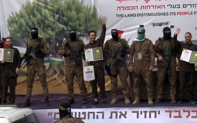 Eliya Cohen (L), Omer Shem Tov and Omer Wenkert, flanked by armed fighters, wave on stage at a Hamas propaganda ceremony for their release in Gaza on February 22, 2025 (Screen grab/YouTube)