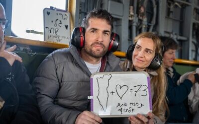 Freed hostage Sagui Dekel-Chen with his wife Avital aboard an IDF helicopter en route to the hospital soon after his release from 498 days in Hamas captivity in Gaza, February 15, 2025. The whiteboard message refers to the then-73 hostages still held in Gaza, and urges 'return all of them to us.' (IDF)