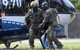 Members of a special police unit escort a man suspected to be responsible for the Solingen knife attack from a helicopter to the office of the Federal Prosecutor in Karlsruhe, southern Germany, on August 25, 2024. (Thomas Kienzle / AFP)