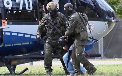 Members of a special police unit escort a man suspected to be responsible for the Solingen knife attack from a helicopter to the office of the Federal Prosecutor in Karlsruhe, southern Germany, on August 25, 2024. (Thomas Kienzle / AFP)