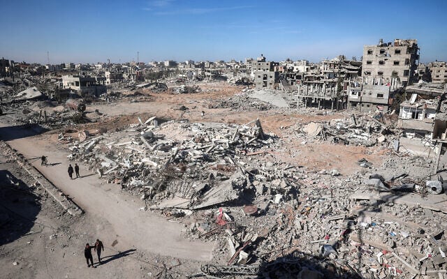 File: People walk past building rubble in a ruined neighborhood in Rafah in the southern Gaza Strip on January 21, 2025 (Eyad BABA / AFP)