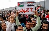A man hoists a sign reading "No to displacement" at a demonstration against US President Donald Trump's plan to take over Gaza, on the Egyptian side of the Strip's Rafah Border Crossing, January 31, 2025. (Kerolos Salah / AFP)