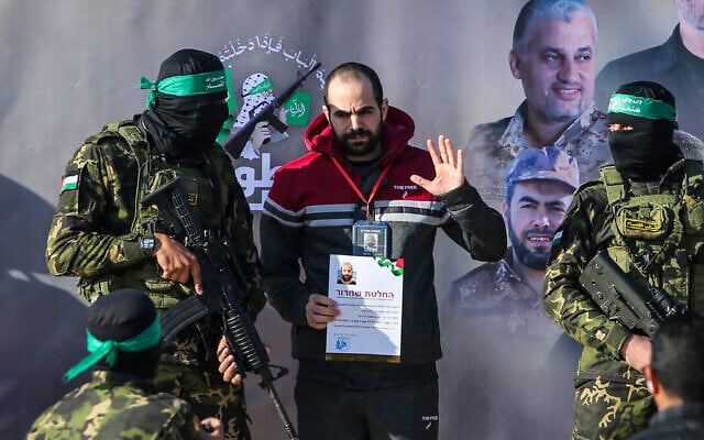 Hamas gunmen flank Israeli hostage Yarden Bibas on a stage before handing him over to a Red Cross team in Khan Yunis on February 1, 2025, as part of a hostage-ceasefire deal. (Eyad BABA / AFP)