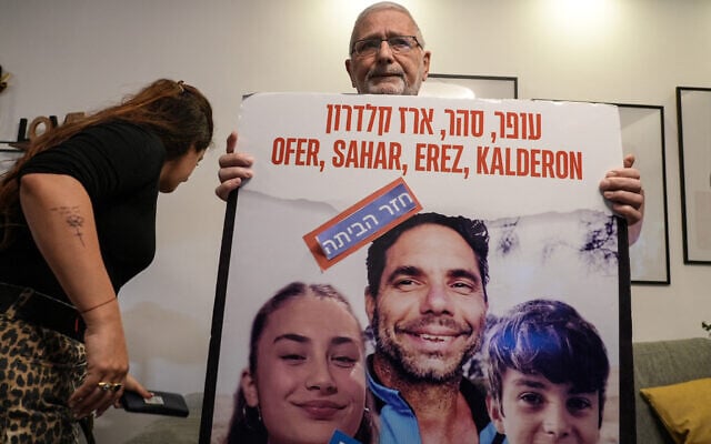 A Member of Ofer Calderon's family holds a poster bearing his picture with the a note in Hebrew added on it that reads "back home", his release from captivity in the Gaza Strip on February 1, 2025, at the family home in Kfar Saba. (Photo by Sharon  ARONOWICZ / AFP)