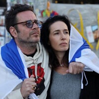 A man and a woman draped in an Israeli flag watch the release by the Hamas terror group of hostages Ofer Calderon and Yarden Bibas in the Gaza Strip, on a screen at Hostages Square in Tel Aviv,  on February 1, 2025.  (Photo by Jack GUEZ / AFP)