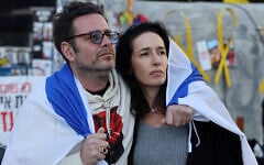 A man and a woman draped in an Israeli flag watch the release by the Hamas terror group of hostages Ofer Calderon and Yarden Bibas in the Gaza Strip, on a screen at Hostages Square in Tel Aviv,  on February 1, 2025.  (Photo by Jack GUEZ / AFP)