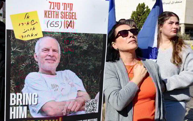 People standing next to a poster of  hostage Keith Siegel react as they watch his release on a screen at hostage square in Tel Aviv on February 1, 2025.  (Photo by Jack GUEZ / AFP)