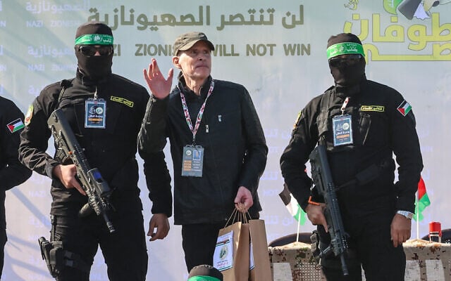 Hamas gunmen escort American-Israeli hostage Keith Siegel on a stage before handing him over to a Red Cross team in Gaza City on February 1, 2025, as part of the fourth hostage-prisoner exchange. (Photo by Omar AL-QATTAA / AFP)