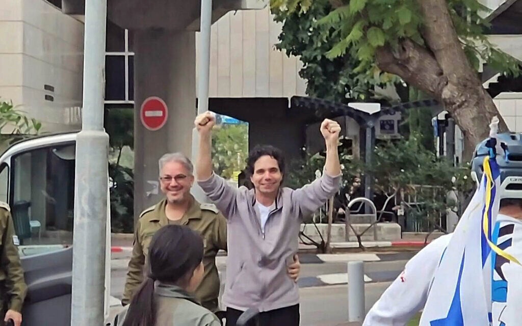 Freed hostage Ofer Calderon raises both hands and blows kisses to friends outside the Sheba Medical Center on his return to Israel, February 1, 2025. (Eyal Hadani/AFP)