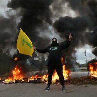 A man waves a Hezbollah flag as protesters burn tires to block the road leading to Beirut's international airport, following the visit of US Deputy Special Envoy for the Middle East Morgan Ortagus, during which she met with the country's president, on February 7, 2025. (IBRAHIM AMRO / AFP)
