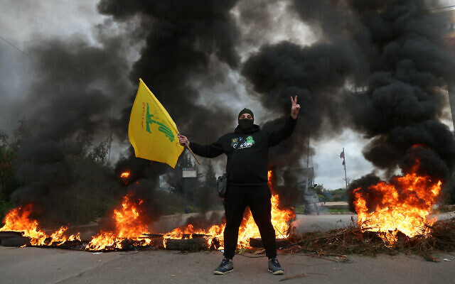 A man waves a Hezbollah flag as protesters burn tires to block the road leading to Beirut's international airport, following the visit of US Deputy Special Envoy for the Middle East Morgan Ortagus, during which she met with the country's president, on February 7, 2025. (IBRAHIM AMRO / AFP)