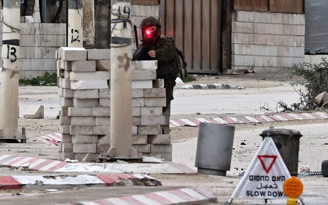 An Israeli soldier takes aim as he mans a checkpoint during raid in the Nur Shams refugee camp near Tulkarem in the West Bank on February 9, 2025. (Zain JAAFAR / AFP)