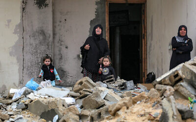 Women and children stand by the rubble of a collapsed building outside another building at the Shati camp for Palestinian refugees north of Gaza City on February 11, 2025 (BASHAR TALEB / AFP)