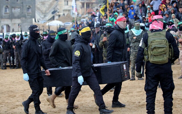 Palestinian terrorists carry one of the coffins said to carry the bodies of four slain Israeli hostages to the Red Cross in Khan Younis in the Gaza on February 20, 2025. (Eyad BABA / AFP)