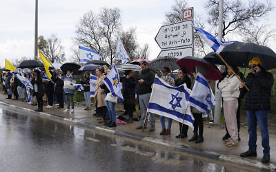 People pay their respects while waiting for a convoy with the bodies said to be of four Israeli hostages near the southern city of Sderot on February 20, 2025 (John Wessels / AFP)