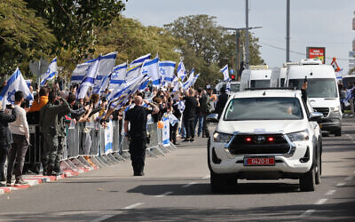 Israelis wave the national flag as the convoy of vehicles transporting what are believed to be the bodies of four Israeli hostages handed over by Hamas arrives at the entrance to the National Center of Forensic Medicine in Tel Aviv on February 20, 2025. (Jack GUEZ / AFP)