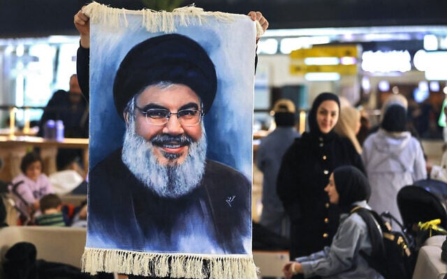 A Lebanese youth holds a portrait of slain Hezbollah leader Hassan Nasrallah at Baghdad airport as he waits to board a flight to Beirut on February 20, 2025. (AHMAD AL-RUBAYE / AFP)