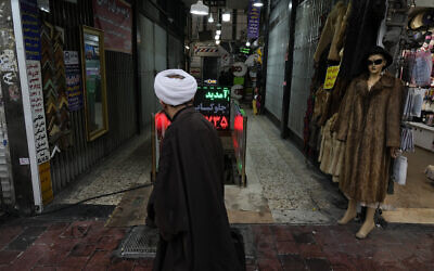 A cleric walks in front of a shopping center in northern Tehran, Iran on January 27, 2025. (AP Photo/Vahid Salemi)