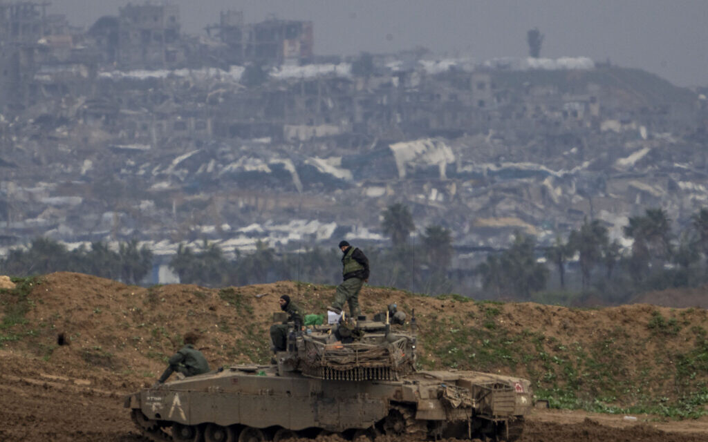Israeli soldiers work on their tank in southern Israel, with a view of he Gaza Strip in the background, February 11, 2025. (AP Photo/Ariel Schalit)