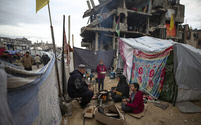 A Palestinian family cooks on fire next to their tent, in an area largely destroyed during the war against Hamas in Jabaliya, Gaza Strip, February 11, 2025. (Jehad Alshrafi/AP)