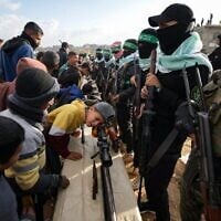 A child looks into a weapon as Hamas gunmen take up a position ahead of handing over the bodies of four slain Israeli hostages, including a mother and her two children, to the Red Cross in Khan Younis, southern Gaza Strip, Feb. 20, 2025. (AP Photo/Jehad Alshrafi)