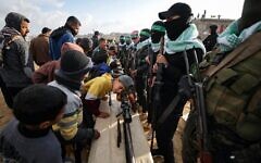 A child looks into a weapon as Hamas gunmen take up a position ahead of handing over the bodies of four slain Israeli hostages, including a mother and her two children, to the Red Cross in Khan Younis, southern Gaza Strip, Feb. 20, 2025. (AP Photo/Jehad Alshrafi)
