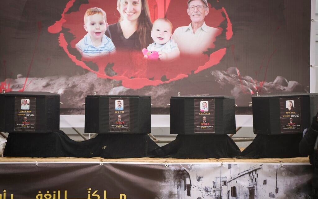 Coffins apparently containing the bodies of slain Israeli hostages Shiri Bibas, her two children Ariel and Kfir, and Oded Lifshitz, are displayed on a stage with a propaganda message before being handed over to the Red Cross by Hamas and Islamic Jihad terrorists in Khan Younis, Gaza Strip, Feb. 20, 2025. (AP Photo/Abdel Kareem Hana)