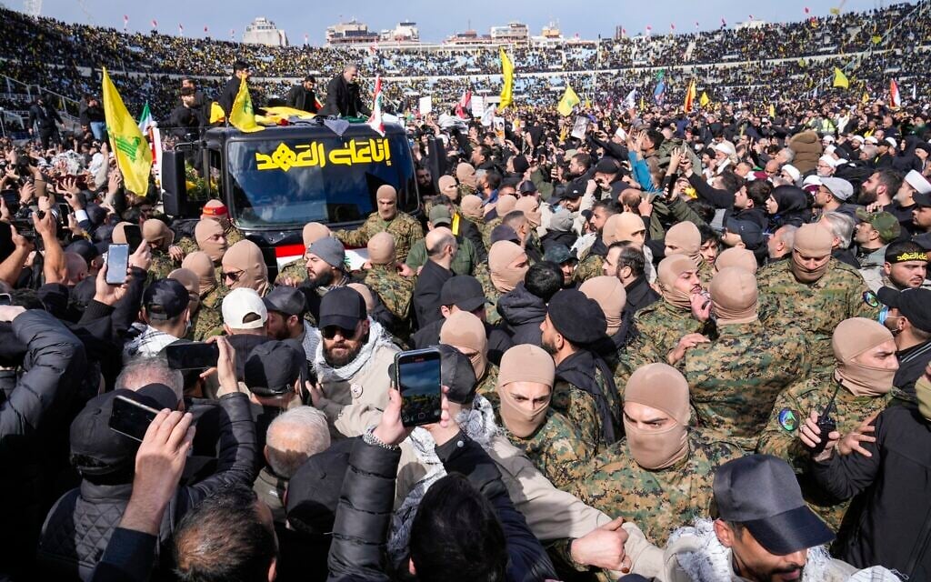 A trailer carrying the coffins containing the bodies of Hezbollah's former leader Hassan Nasrallah and his cousin and successor Hashem Safieddine drives through the crowd at the beginning of a funeral procession in the Sports City Stadium in Beirut, Lebanon, Feb. 23, 2025. (AP Photo/Hussein Malla)