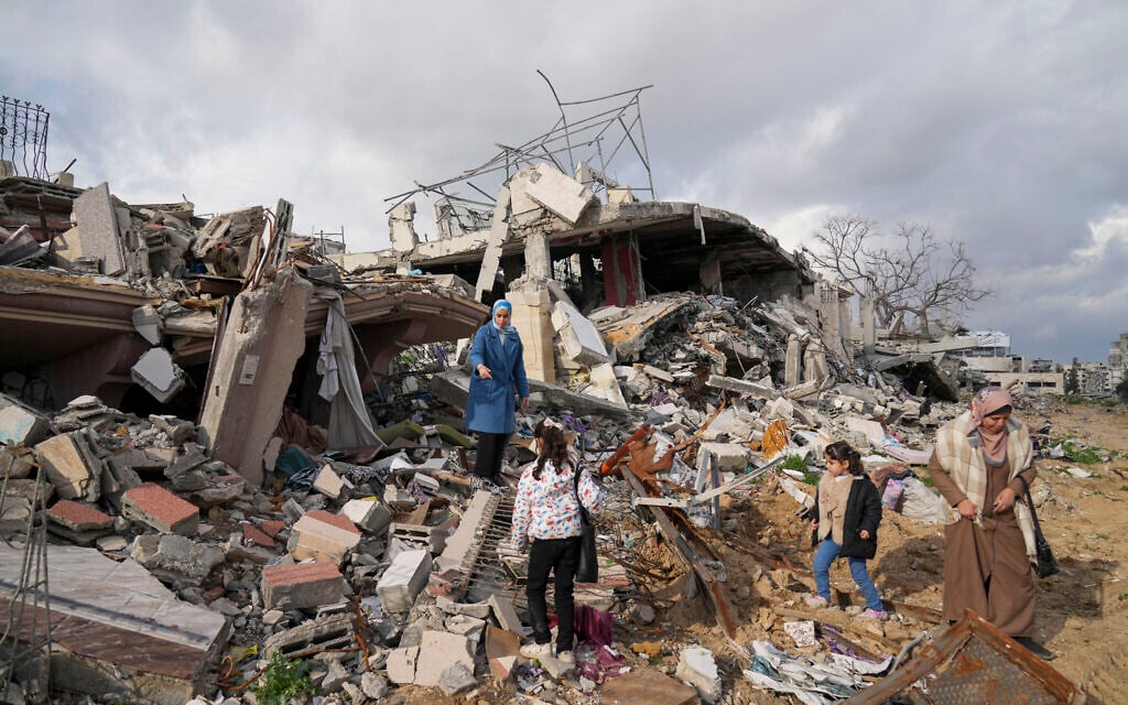 Members of the Dwaima family stand on the rubble of their home, which was leveled by an Israeli airstrike during the Israel-Hamas war, in the Tal al Hawa neighborhood in Gaza City, Feb. 24, 2025. (AP/Abdel Kareem Hana)