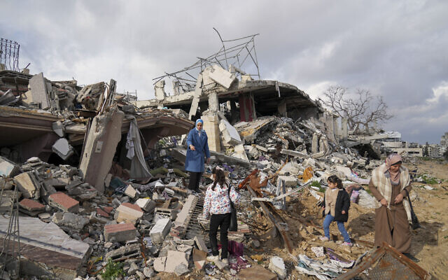 Members of the Dwaima family stand on the rubble of their home, which was leveled by an Israeli airstrike during the Israel-Hamas war, in the Tal al Hawa neighborhood in Gaza City, Feb. 24, 2025. (AP/Abdel Kareem Hana)