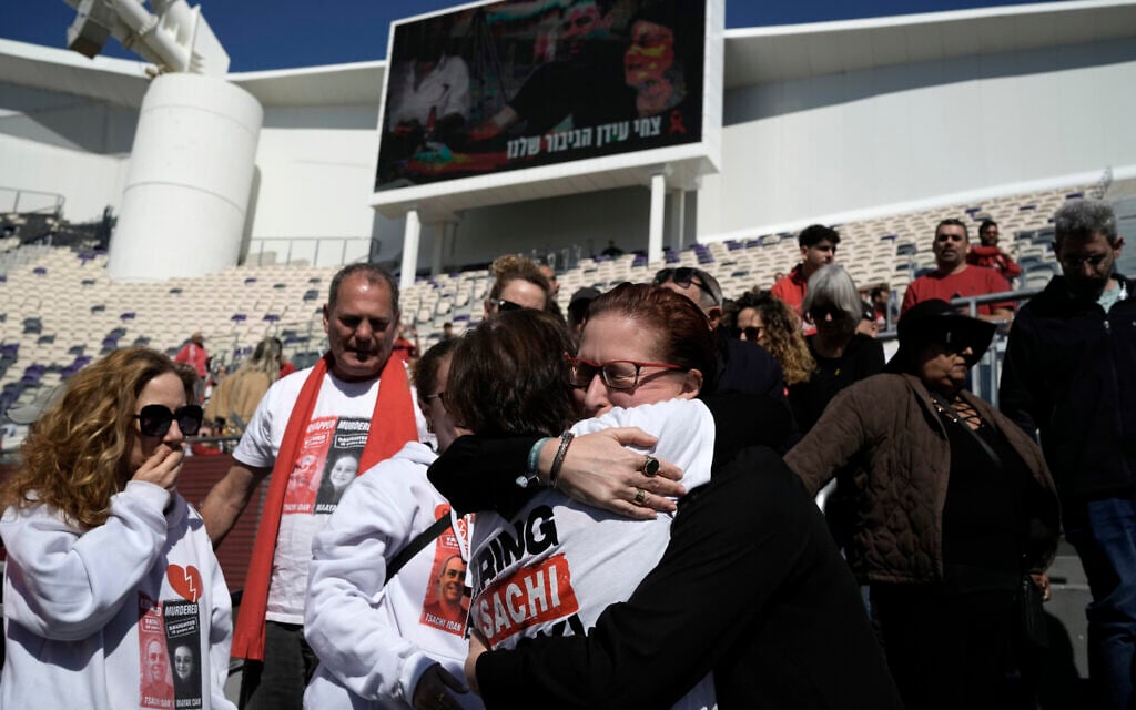 Mourners embrace at a public memorial ceremony for slain hostage Tsachi Idan, a fan of Hapoel Tel Aviv, who was killed in Hamas captivity in the Gaza Strip, at Bloomfield Stadium in Tel Aviv, Feb. 28, 2025. (AP/Leo Correa)